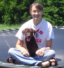 Girl sitting cross-legged on a trampoline with a puppy in her lap